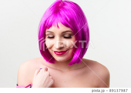 Face of a young woman with bright makeup on a pink background with gathered hair in a smooth ponytail. Face of a young woman with bright makeup on a pink background with gathered hair in a smooth ponytail. 89137987