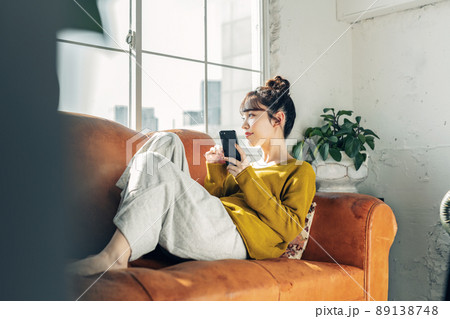 ソファーでスマホを持つ女性 ソファーでスマホを持つ女性 89138748