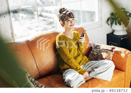 ソファーでスマホを持つ女性 89138752