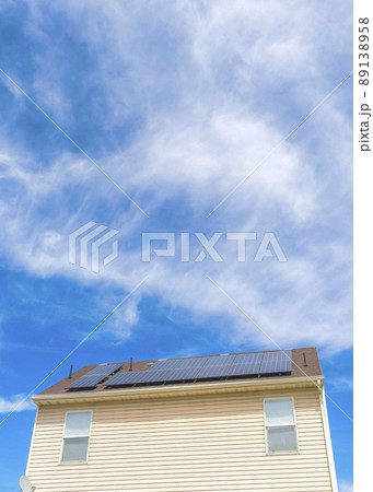 Vertical Whispy white clouds Low angle view of two houses with wood vinyl sidings and solar panels on roof at Utah valley 89138958
