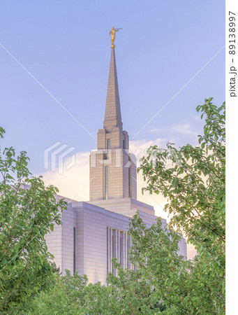 Vertical Puffy clouds at sunset Concrete path with columnar trees on both sides leading to the church 89138997