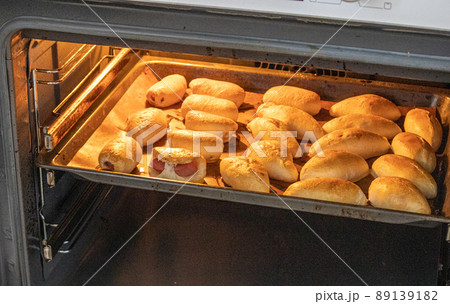 The concept of cooking homemade food, freshly baked hot pies with filling on a baking sheet in the oven The concept of cooking homemade food, freshly baked hot pies with filling on a baking sheet in the oven 89139182