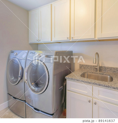 Square Laundry interior with front load laundry units and vanity sink Square Laundry interior with front load laundry units and vanity sink 89141637