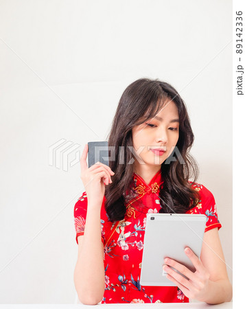 Asian young woman wearing traditional cheongsam qipao dress using digital tablet and credit card shopping online, e-commerce concept isolated on white background. Asian young woman wearing traditional cheongsam qipao dress using digital tablet and credit card shopping online, e-commerce concept isolated on white background. 89142336