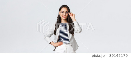 Business, finance and employment, female successful entrepreneurs concept. Confident businesswoman in glasses and white suit ready for meeting, smiling pleased, standing determined Business, finance and employment, female successful entrepreneurs concept. Confident businesswoman in glasses and white suit ready for meeting, smiling pleased, standing determined 89145179