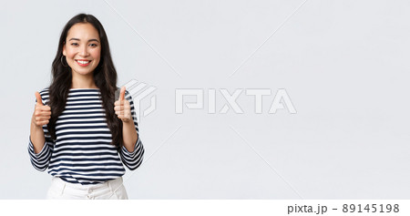 Lifestyle, beauty and fashion, people emotions concept. Satisfied and impressed happy female customer recommend awesome beauty salon or shopping site, showing thumbs-up in approval 89145198