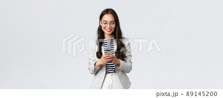Business, finance and employment, female successful entrepreneurs concept. Businesswoman waiting for client, checking messages in smartphone, wearing glasses as looking at mobile screen 89145200