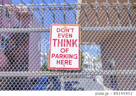 Don't even think of parking here signage on a metal mesh fence in San Francisco, California 89145952