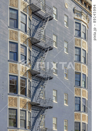 Apartment building exterior with gray wall and metal emergency stairs outdoors 89145994