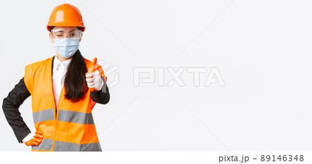 Covid-19 safety protocol at enterpise, construction and preventing virus concept. Confident asian female engineer, architect in face mask and helmet showing thumb-up, guarantee quality of building Covid-19 safety protocol at enterpise, construction and preventing virus concept. Confident asian female engineer, architect in face mask and helmet showing thumb-up, guarantee quality of building 89146348