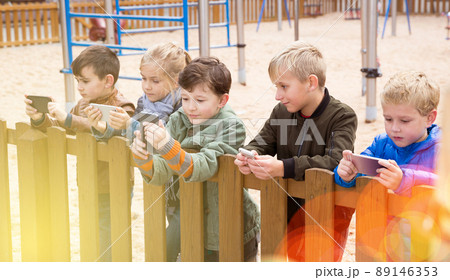 Children with phones near wooden fence 89146353