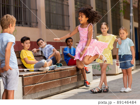Smiling kids skipping on jumping elastic rope in yard Smiling kids skipping on jumping elastic rope in yard 89146484