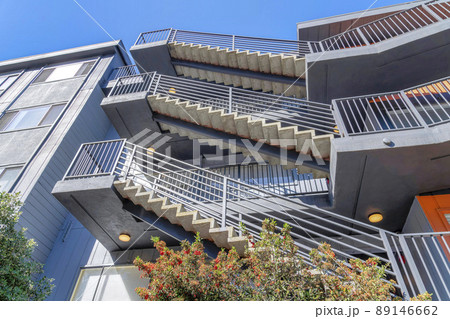 Low angle view of an apartment building with three outdoor straight staircase with metal railings 89146662