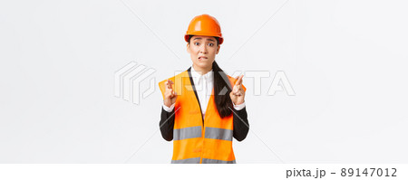 Worried hopeful asian female architect feeling nervous as waiting for inspection results at construction area, wearing safety helmet, cross fingers good luck, hope everything be well Worried hopeful asian female architect feeling nervous as waiting for inspection results at construction area, wearing safety helmet, cross fingers good luck, hope everything be well 89147012