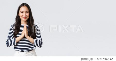 Lifestyle, people emotions and casual concept. Cute asian girl in casual outfit smiling as saying namaste, holding hands in pray, pleading or greeting guests with polite bow Lifestyle, people emotions and casual concept. Cute asian girl in casual outfit smiling as saying namaste, holding hands in pray, pleading or greeting guests with polite bow 89148732