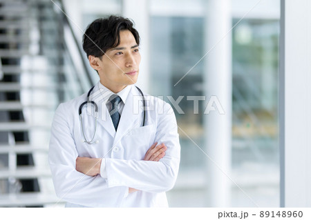 病院内で腕組みする白衣の若い男性医師 89148960