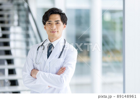 病院内で腕組みする白衣の若い男性医師 89148961