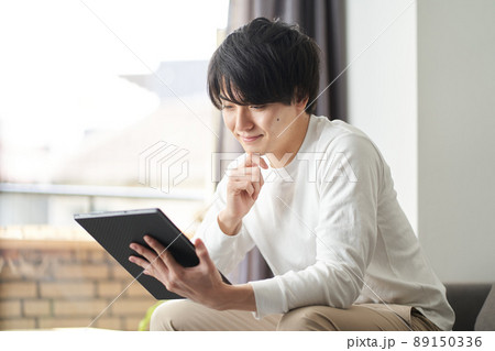 自宅のリビングでタブレットを使うアジア人男性 自宅のリビングでタブレットを使うアジア人男性 89150336