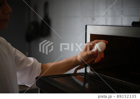 電子レンジで卵を温めようとする男性 電子レンジで卵を温めようとする男性 89152135