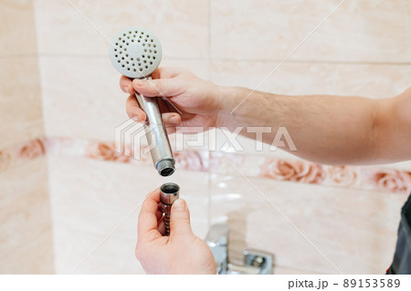 A male plumber repairs the shower head in the bathroom. A male plumber repairs the shower head in the bathroom. 89153589