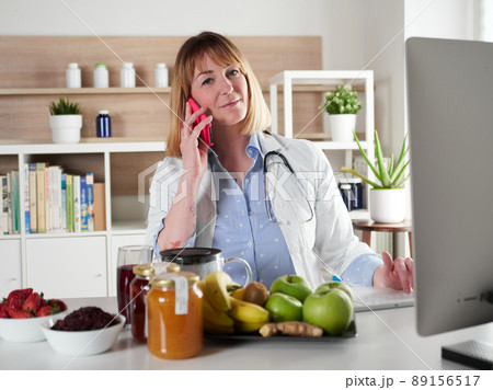 distracted female nutritionist chatting with smartphone in office studio distracted female nutritionist chatting with smartphone in office studio 89156517