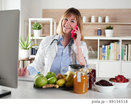 distracted female nutritionist chatting with smartphone in office studio 89156518