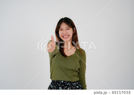 Young asian woman standing over isolated white background happy face smile looking at the camera. Positive person. 89157038