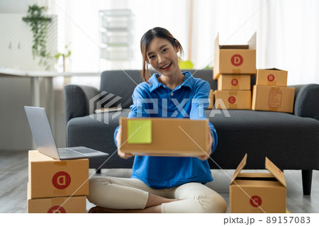Young Asian Woman holding parcel box for delivery to customer by logistic service. small business entrepreneur SME distribution warehouse. small owner home office and Online marketing product theme 89157083