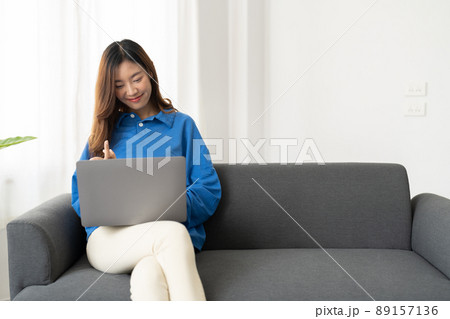 Young asian business woman work from home with laptop computer online to internet on sofa, freelance girl using notebook on couch with comfort, new normal, lifestyle concept with copyspace Young asian business woman work from home with laptop computer online to internet on sofa, freelance girl using notebook on couch with comfort, new normal, lifestyle concept with copyspace 89157136