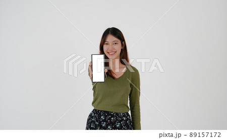 Image of young asian girl holding smartphone show blank white screen on white background. 89157172
