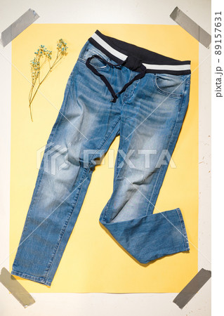 blue women's jeans lie on yellow background 89157631