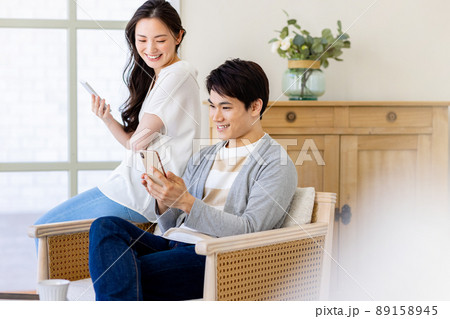 家でリラックスしながらスマホを操作する夫婦 家でリラックスしながらスマホを操作する夫婦 89158945