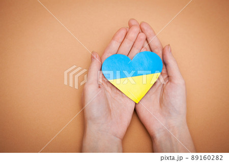Heart with print the national flag of ukraine in female hands. Heart with print the national flag of ukraine in female hands. 89160282