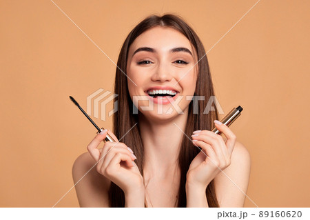 woman hold mascara isolated on beige background woman hold mascara isolated on beige background 89160620