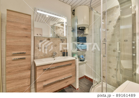 Bathroom with glazed shower stall, ceramic sink surrounded by white tiles in a modern house 89161489