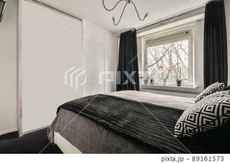 The interior of a bedroom with a black and gray design and a large window in a cozy apartment The interior of a bedroom with a black and gray design and a large window in a cozy apartment 89161573