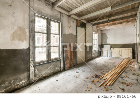 An old building that needs renovation with large windows and a door in the center 89161766