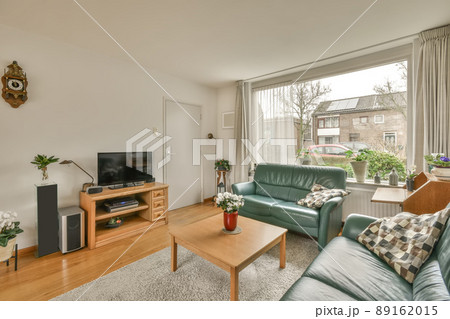 The interior of the living room with two sofas in front of the TV near to the big window in a cozy house 89162015