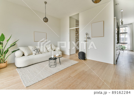 A spacious, bright living room with a large white sofa on the carpet in a cozy house A spacious, bright living room with a large white sofa on the carpet in a cozy house 89162284