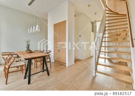 Interior of the dining area next to the stairs to the top and a vase of flowers on the table 89162517