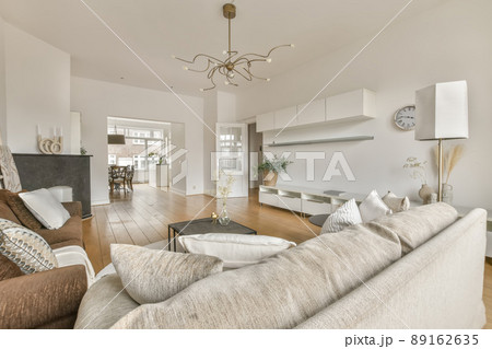 Living room with comfortable sofas on the parquet floor and access to the dining room in a modern house 89162635