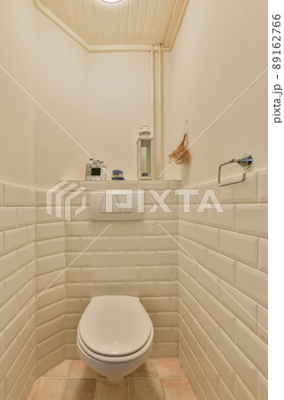Bathroom interior with a hinged toilet surrounded by white tiles Bathroom interior with a hinged toilet surrounded by white tiles 89162766