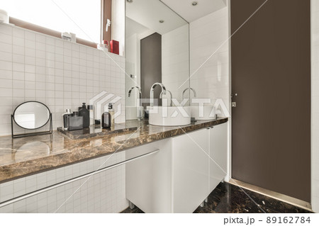 Marble bathroom with two ceramic sinks and a large mirror 89162784
