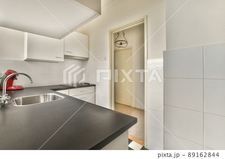 A small kitchen with lots of cabinets and a metal sink on the tiled floor A small kitchen with lots of cabinets and a metal sink on the tiled floor 89162844