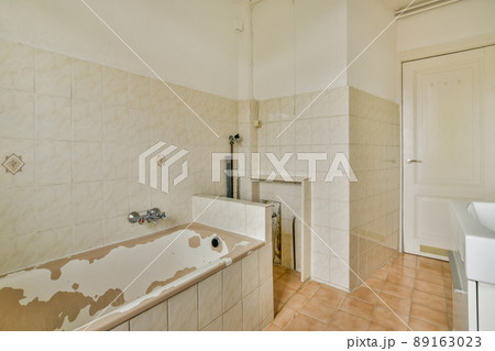 A small, old-fashioned bathroom with a marble-style tile bathtub and sink A small, old-fashioned bathroom with a marble-style tile bathtub and sink 89163023