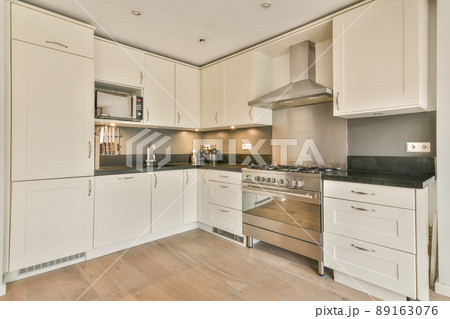 A small corner kitchen in white on a parquet floor in a cozy house 89163076
