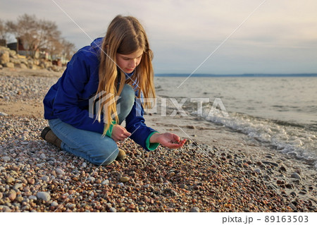 Young Adolescent Girl Collects Beautiful Rocks Pebbles and Shells on the Beach Along Georgian Bay 89163503