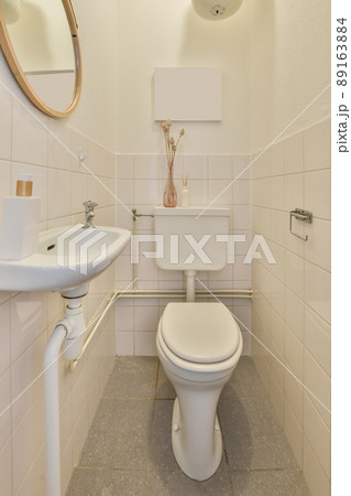Bathroom interior in white tones with a toilet and ceramic sink under the mirror Bathroom interior in white tones with a toilet and ceramic sink under the mirror 89163884