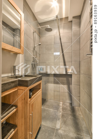 The interior of the bathroom in gray tones with a marble sink and a glass shower cabin The interior of the bathroom in gray tones with a marble sink and a glass shower cabin 89163939