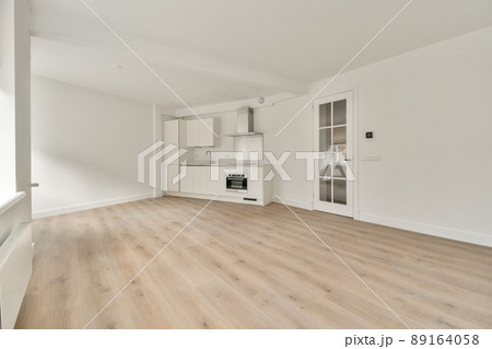 Large room in an empty new house with a corner kitchen in a minimalist style, made in white Large room in an empty new house with a corner kitchen in a minimalist style, made in white 89164058